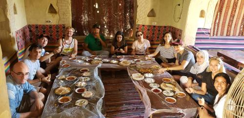 Un groupe de personnes assises autour d'une table dans l'établissement Mountain Camp Ali Khaled, à Siwa