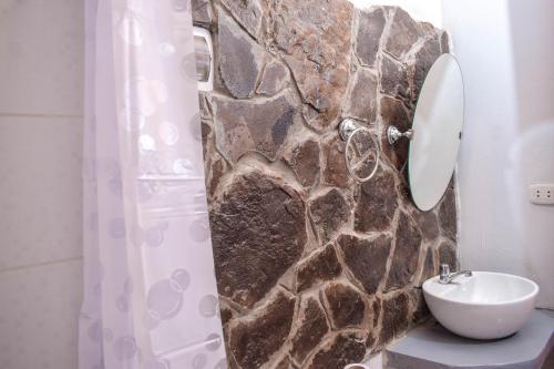 baño con lavabo y pared de piedra en YUMBILLA ECO LODGE, en Cuispes