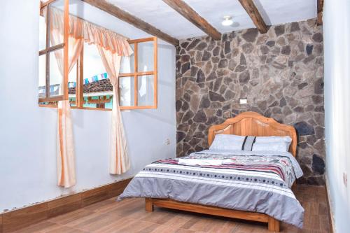 1 dormitorio con cama y pared de piedra en YUMBILLA ECO LODGE, en Cuispes