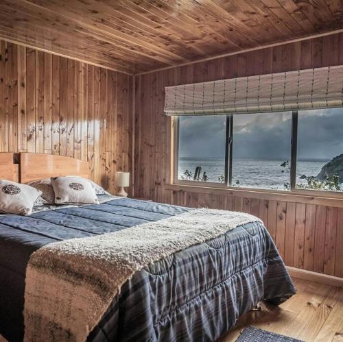 a bedroom with a bed with a view of the ocean at Hostería La Casa del Mar in Bahía Mansa