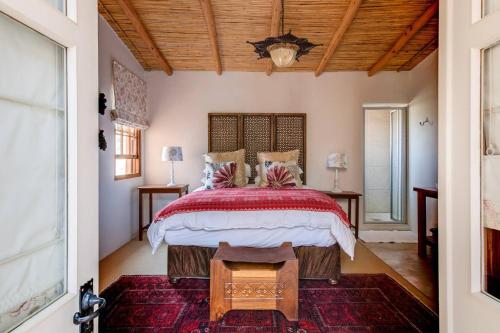 a bedroom with a large bed and a wooden ceiling at Nooitgedacht Country House in Boesmanspad