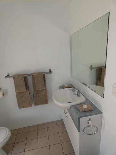 a white bathroom with a sink and a toilet at Aroa Kainga Bungalows and Apartment in Rarotonga