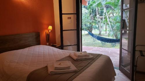 a bedroom with a bed with towels and a window at Gamboa Eco Refugio Pousada in Iporanga