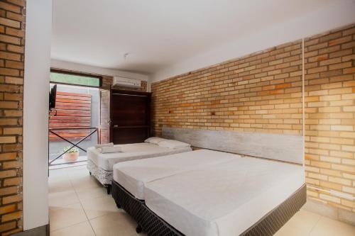 2 Betten in einem Zimmer mit Ziegelwand in der Unterkunft Economy Flat in Natal