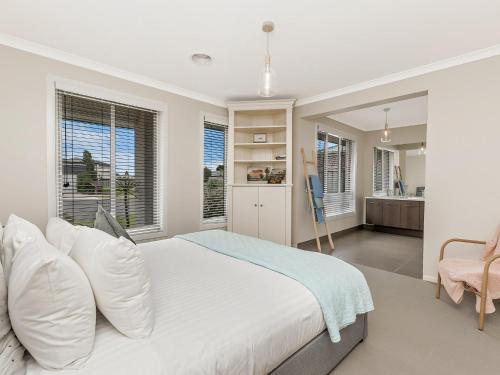 a white bedroom with a large bed and windows at Little Croft in Port Fairy