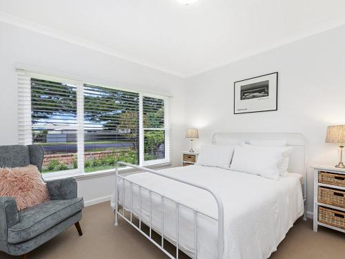 a white bedroom with a bed and a chair at Marlow House in Port Fairy