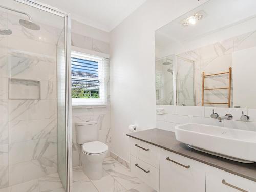 a white bathroom with a toilet and a sink at Marlow House in Port Fairy