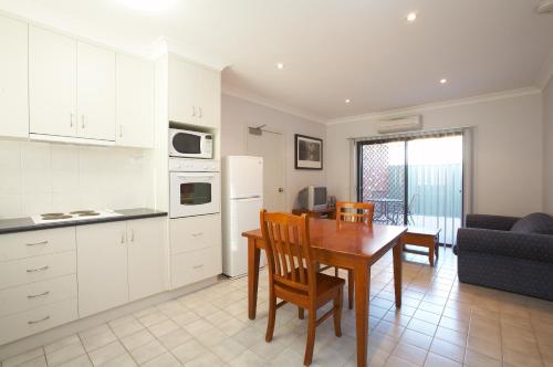 a kitchen and a dining room with a table and a couch at Belvoir Village Motel & Apartments Wodonga in Wodonga
