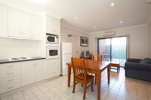 a kitchen with a table, chairs and a refrigerator at Belvoir Village Motel & Apartments Wodonga in Wodonga