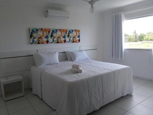 a bedroom with a white bed with two teddy bears on it at condomínio Mar da Galiléia in Coroa Vermelha