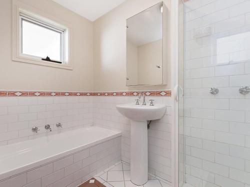 a white bathroom with a sink and a bath tub at Moyne Views 2 in Port Fairy