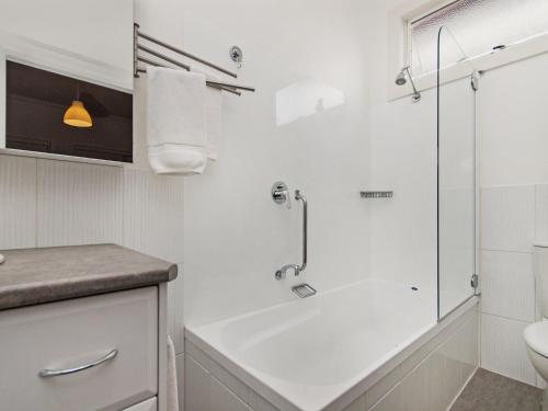 a white bathroom with a shower and a sink at Railway Cottage in Port Fairy