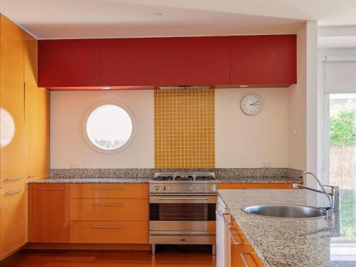 a kitchen with red cabinets and a sink and a window at Rubys Beachfront in Port Fairy