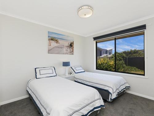 two beds in a room with a window at Seaclusion in Port Fairy