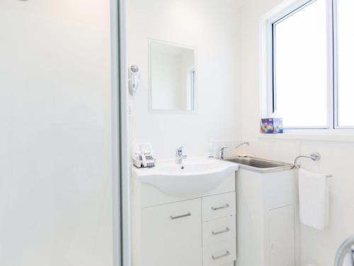 a white bathroom with a sink and a mirror at Sheoaks Cottage in Port Fairy