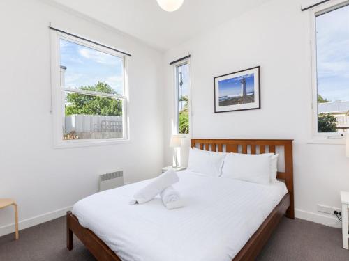 a white bedroom with a bed and two windows at The Church in Port Fairy