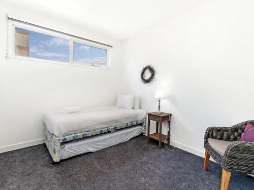 a bedroom with a bed and a window and a chair at The Townhouse in Port Fairy