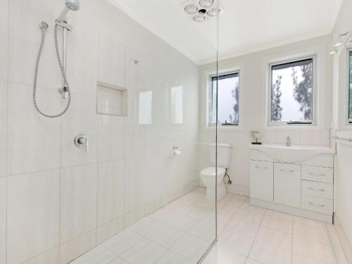 a white bathroom with a shower and a toilet at Waters Edge in Port Fairy
