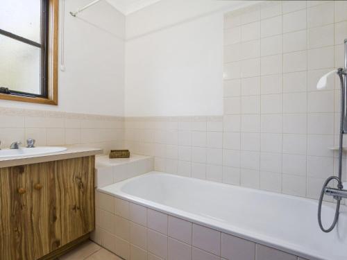 La salle de bains est pourvue d'une baignoire et d'un lavabo. dans l'établissement Whalers Cottage, à Port Fairy