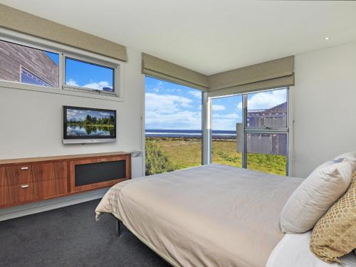 a bedroom with a bed and a tv and windows at Whispers in Port Fairy