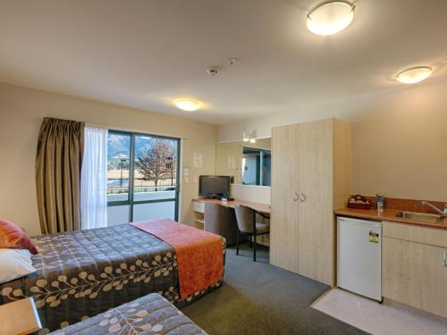 a hotel room with a bed and a desk and a kitchen at Bella Vista Hanmer Springs in Hanmer Springs