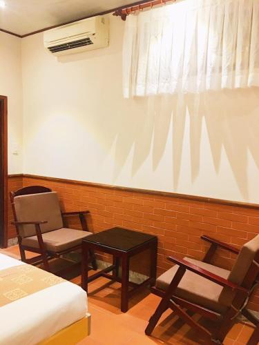 a room with a bed and two chairs and a table at Sầm Sơn Boutique Hotel Phan Thiết in Phan Thiet