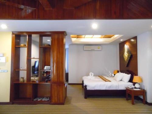 a bedroom with a bed and a television in it at Charming Lao Hotel in Ban Chéng