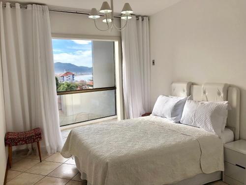 1 dormitorio con cama y ventana grande en Apto Ingleses Mar, en Florianópolis