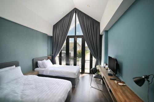 a bedroom with two beds and a desk with a television at The Nichehome Waterside Living in Chiang Mai