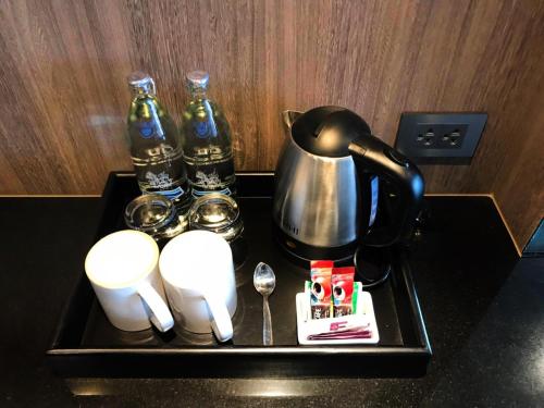 a tray with a tea kettle and cups and drinks at Fortune View Khong Hotel Nakhon Phanom in Nakhon Phanom