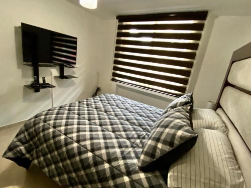 a bedroom with a bed and a flat screen tv at Condominio Renoir in Mexico City