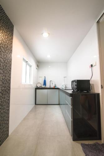 a kitchen with white walls and a counter with a microwave at Landed Cozy House Near SPICE, Airport in Kampong Manggis