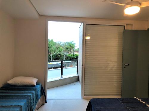 a bedroom with a sliding glass door to a balcony at Casa na praia LINDA de JUQUEHY in São Sebastião