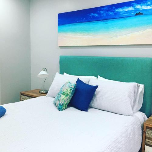 a bedroom with a white bed with blue pillows at Sussex Palms Holiday Park in Sussex inlet