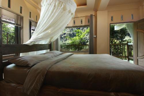 a bedroom with a bed with a mosquito net at Kupu Kupu Garden Guest House & Cafe in Bukit Lawang