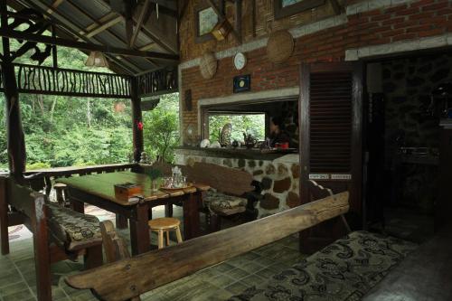 a dining room with a wooden table and a bench at Kupu Kupu Garden Guest House & Cafe in Bukit Lawang