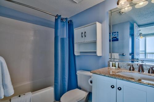a bathroom with a toilet and a sink and a mirror at Pelican Beach Resort Destin in Destin