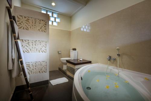 a bathroom with a bath tub and a toilet at Nang Ade Villa by Pramana Villas in Ubud