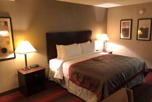 a hotel room with a bed and two lamps at Ramada by Wyndham Michigan City in Michigan City