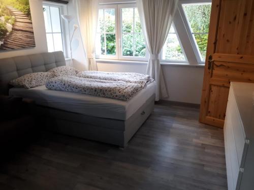 een slaapkamer met een bed voor 2 ramen bij Apartment im Schwarzwaldhaus in Schluchsee