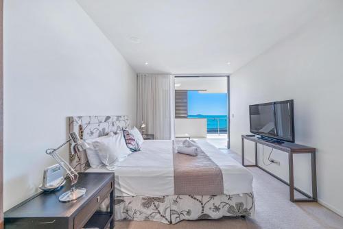 Airlie Beach的住宿－坎農韋爾私語灣行政公寓，一间卧室配有一张大床和电视