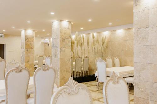 a dining room with white chairs and a table at Aqua Spa Hotel Zlatograd in Zlatograd
