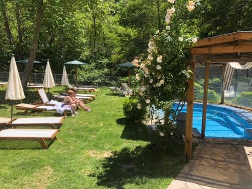a woman sitting on a lawn next to a swimming pool at Family Hotel BOHEMA in Ognyanovo