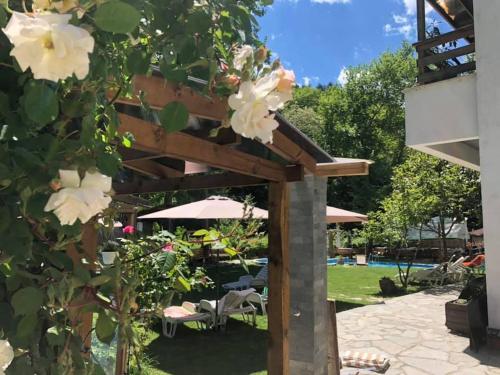a wooden pergola in a garden with flowers at Family Hotel BOHEMA in Ognyanovo