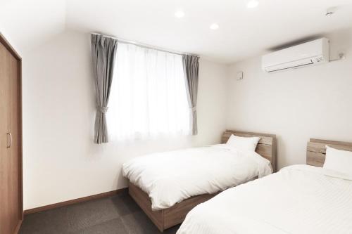 two beds in a room with a window at Villas Fujiyoshida in Fujiyoshida