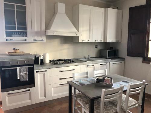 a kitchen with white cabinets and a table with chairs at Casa in campagna a due passi dal mare in Pisa