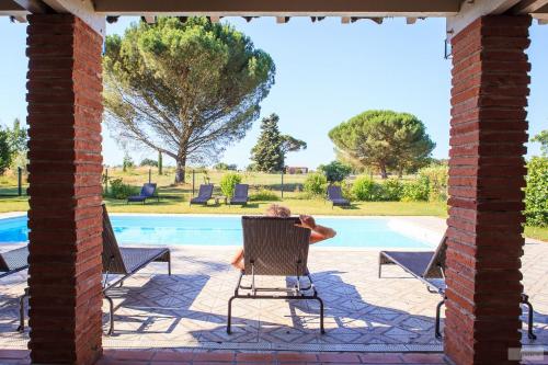 a person sitting in a chair by a swimming pool at Domaine du Buc , les Gîtes de Prestige in Marssac-sur-Tarn