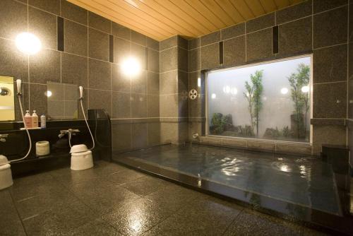 a bathroom with a large window and a bath tub at Hotel Route-Inn Odate Eki Minami in Odate