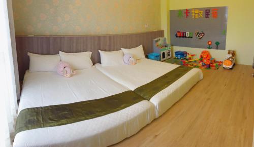 台東市的住宿－米卡撒民宿(親子民宿)，一张大床,上面有两个小猫枕头