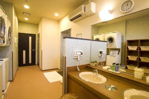 een badkamer met een wastafel en een spiegel bij Hotel Route-Inn Odate Eki Minami in Odate